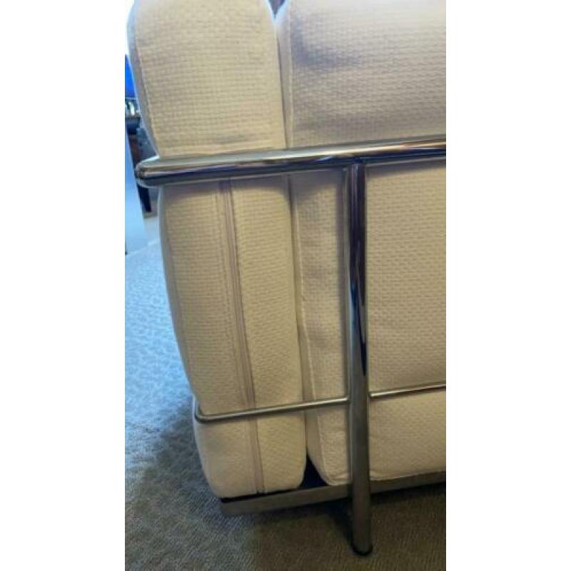 Twee fauteuils met stalen frame en witte kussens met rits