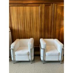 Twee fauteuils met stalen frame en witte kussens met rits