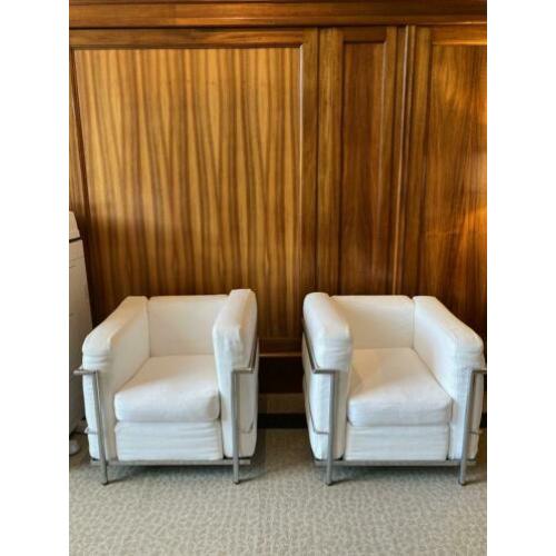 Twee fauteuils met stalen frame en witte kussens met rits