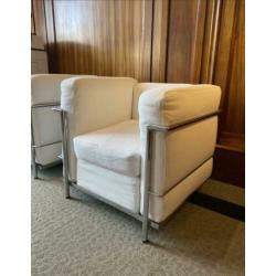 Twee fauteuils met stalen frame en witte kussens met rits