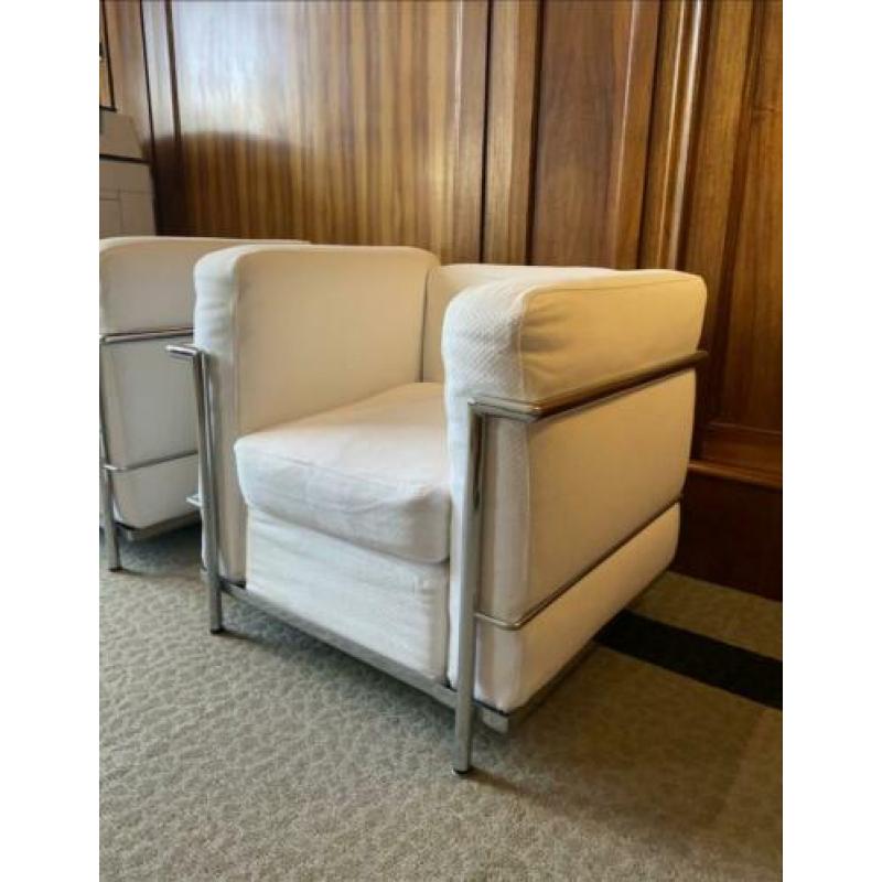 Twee fauteuils met stalen frame en witte kussens met rits